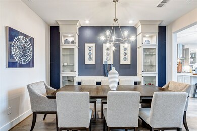 A grand chandelier hangs overhead, casting a warm and inviting glow across the room. Against the walls stand exquisite built-in cabinets, showcasing glass shelves and glass doors that shimmer with sophistication.