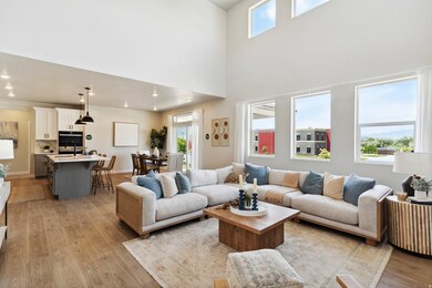 Living room featuring light wood-style flooring, a towering ceiling, and recessed lighting