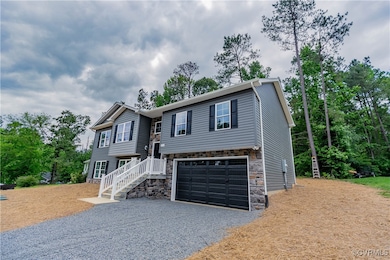 Bi-level home featuring driveway, stone siding, an