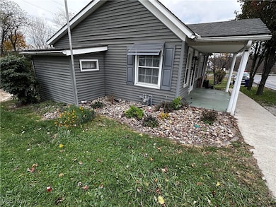 View of side of property featuring a lawn, roof with shingles, and a porch