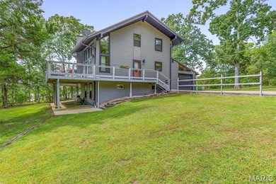 Back of property with a deck, a yard, a chimney, a garage, and stairway