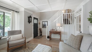 Living area featuring a decorative wall, wood finished floors, stairway, and ornamental molding