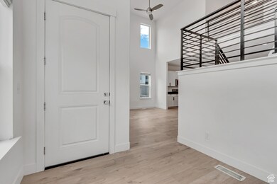 Entrance foyer with a towering ceiling, light wood-type flooring, and ceiling fan