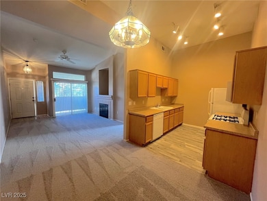 Kitchen featuring open floor plan, light colored carpet, light countertops, white appliances, and hanging light fixtures