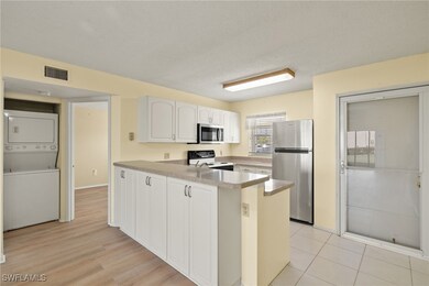 Kitchen with white cabinetry, stacked washer and c