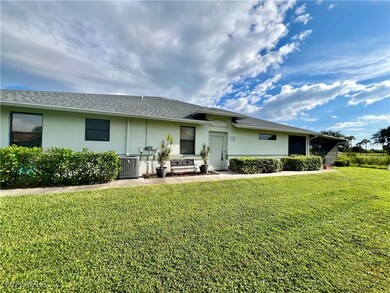 Side of property with central AC unit and a lawn