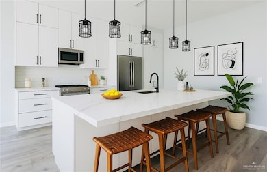 Kitchen with stainless steel appliances, a sink, light wood finished floors, and a kitchen bar