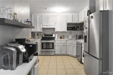 Kitchen featuring appliances with stainless steel finishes, light countertops, white cabinetry, light tile patterned flooring, and open shelves