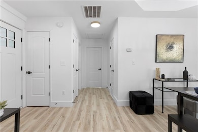 Hall featuring light wood-type flooring, attic acc