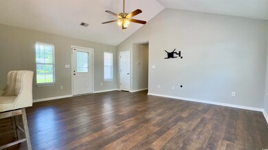 Unfurnished living room featuring ceiling fan, high vaulted ceiling, and dark wood-style flooring