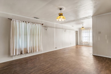 Unfurnished living room with wood walls, dark wood finished floors, and crown molding