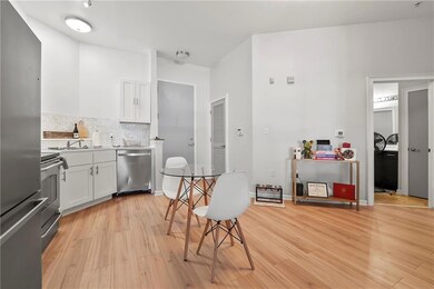 Kitchen with stainless steel appliances, white cabinetry, light wood-style flooring, tasteful backsplash, and light countertops
