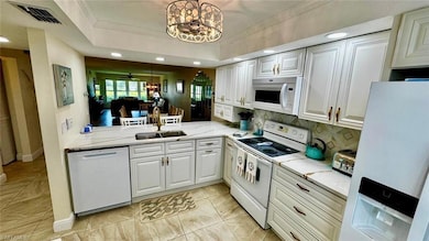 Kitchen featuring white appliances, a sink, a chandelier, tasteful backsplash, and ornamental molding