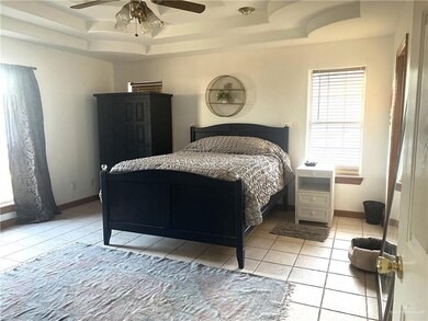 Bedroom featuring ceiling fan, a raised ceiling, and light tile patterned floors