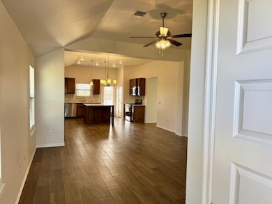 Unfurnished living room featuring dark wood-style floors, vaulted ceiling, a chandelier, and ceiling fan
