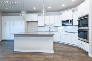 Kitchen with white cabinets, pendant lighting, sta