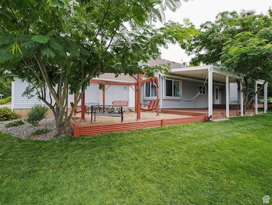 Rear view of house with a patio area, a lawn, an attached carport, and a shingled roof