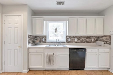 Kitchen with white cabinetry, black dishwasher, vi