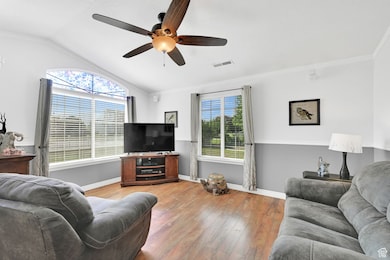 Living area with ceiling fan, light wood-type flooring, lofted ceiling, and ornamental molding