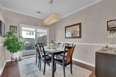 Dining area featuring ornamental molding, baseboards, a chandelier, and wood finished floors