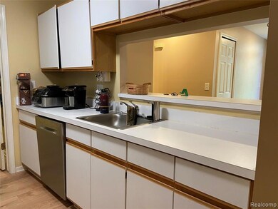 Kitchen with white cabinets, light countertops, light wood-style floors, brown cabinets, and dishwasher