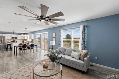 Living room featuring light wood-type flooring, a chandelier, and a ceiling fan