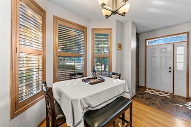 Adjacent to the kitchen is a bright dining area accented by a classic chandelier and a charming bay window with wood plantation shutters, allowing plenty of natural light to fill the space and continuing the home’s warm, cohesive design.