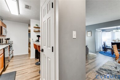 Kitchen featuring light wood finished floors, brown cabinetry, stainless steel appliances, open shelves, and light stone countertops