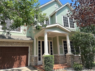 Traditional home with a porch, a garage, stone siding, driveway, and roof with shingles