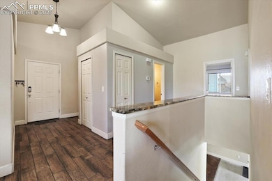 Entrance foyer with dark wood-type flooring, lofted ceiling, and baseboards