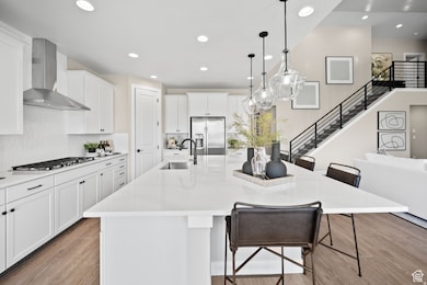Kitchen featuring a breakfast bar area, white cabinetry, a spacious island, recessed lighting, and light wood-type flooring