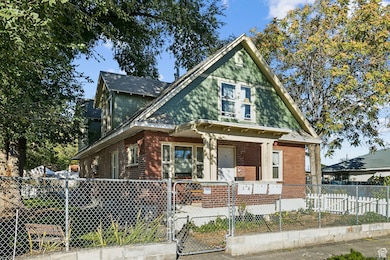 View of front of house with a gate, a fenced front yard, a porch, and brick siding