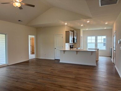 Kitchen with stainless steel appliances, a kitchen bar, a peninsula, a ceiling fan, and dark wood-style flooring