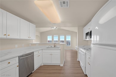 Kitchen with white appliances, a peninsula, visibl