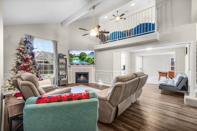 Living room with wood finished floors, a tile fireplace, high vaulted ceiling, beam ceiling, and ceiling fan
