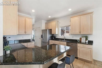 Kitchen featuring light brown cabinetry, a peninsu
