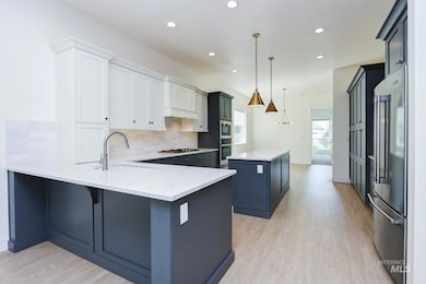 Kitchen featuring backsplash, a center island, a peninsula, stainless steel appliances, and light wood-type flooring