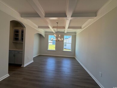 Unfurnished dining area featuring a chandelier, dark wood-style floors, beam ceiling, arched walkways, and coffered ceiling