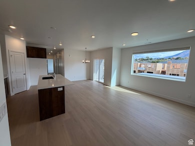 Kitchen with dark brown cabinetry, recessed lighting, open floor plan, a kitchen island with sink, and a chandelier
