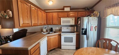 Kitchen featuring brown cabinetry, white appliances, crown molding, and a sink