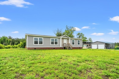 Manufactured / mobile home with crawl space, a garage, an outbuilding, entry steps, and a front lawn