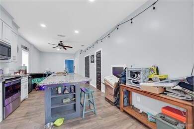 Kitchen with electric stove, white cabinetry, an island with sink, a ceiling fan, and recessed lighting