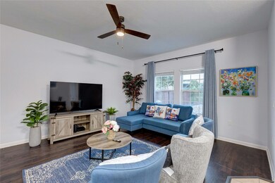 Living room featuring a ceiling fan, baseboards,