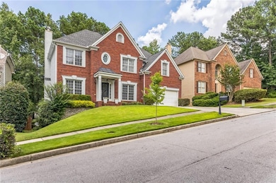 Colonial house featuring concrete driveway, a chimney, an attached garage, brick siding, and a front lawn