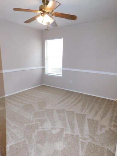 Carpeted spare room with a ceiling fan and basebo