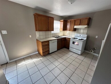 Kitchen with light tile patterned flooring, backsplash, white appliances, tile counters, and sink