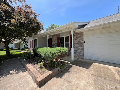 Doorway to property featuring an attached garage, brick siding, driveway, and roof with shingles