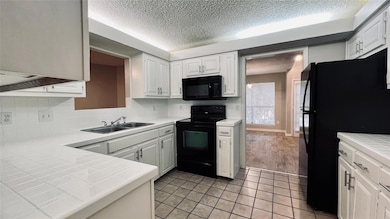 Kitchen featuring black appliances, a sink, a tex