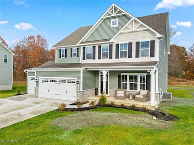 Craftsman-style house with covered porch, stone siding, a front lawn, and driveway