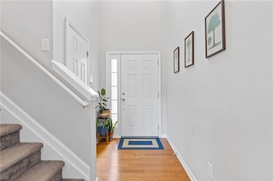 Entrance foyer with wood finished floors, stairway, and baseboards